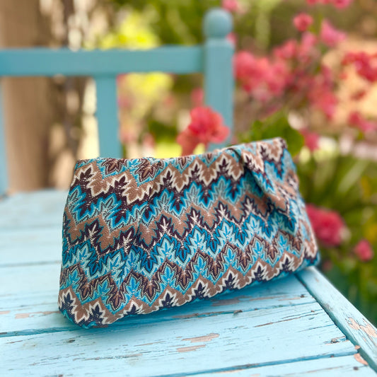 Turquoise and brown knitted fabric clutch bag with magnetic closure.